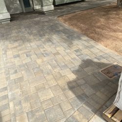 A recently installed stone paver walkway leads to the front entrance of a house with a covered porch.