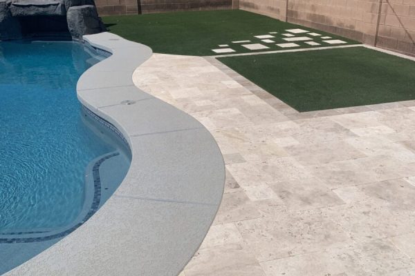 Backyard with a swimming pool, stone patio, artificial grass, and a painted hopscotch game on the grass.
